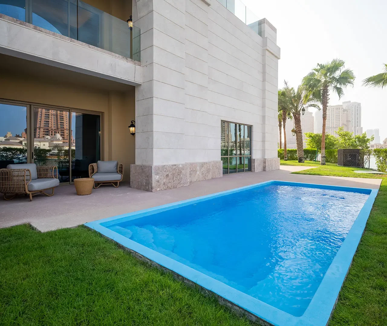 Outdoor pool with patio chairs and palm trees