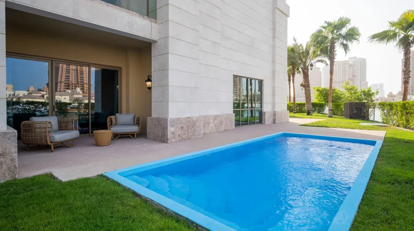 Outdoor pool with patio chairs and palm trees