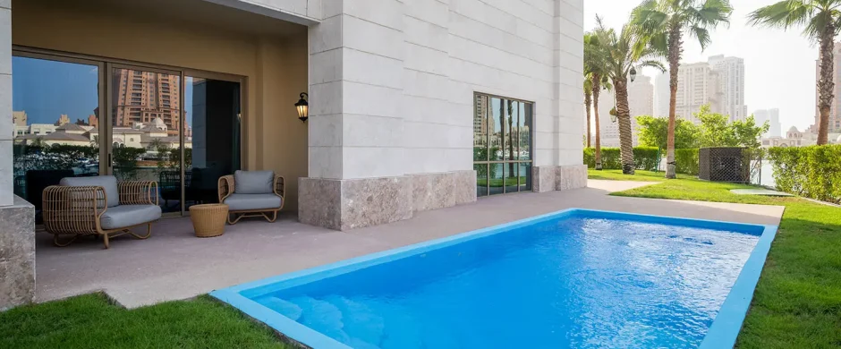 Outdoor pool with patio chairs and palm trees