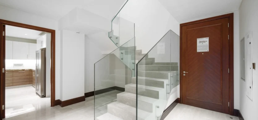 Modern staircase with glass railing near wooden door