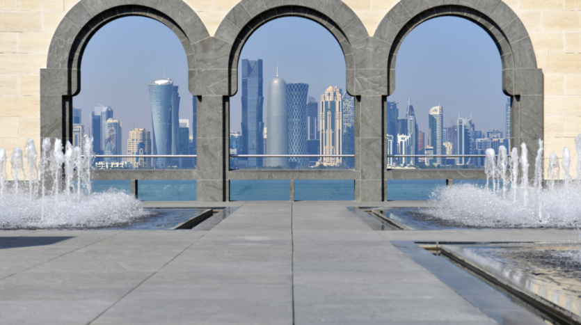 Water fountains and city skyline through arches