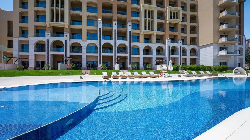 Large curved pool by luxury apartment building.