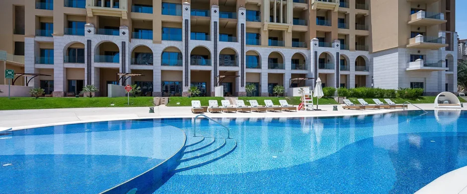 Large curved pool by luxury apartment building.