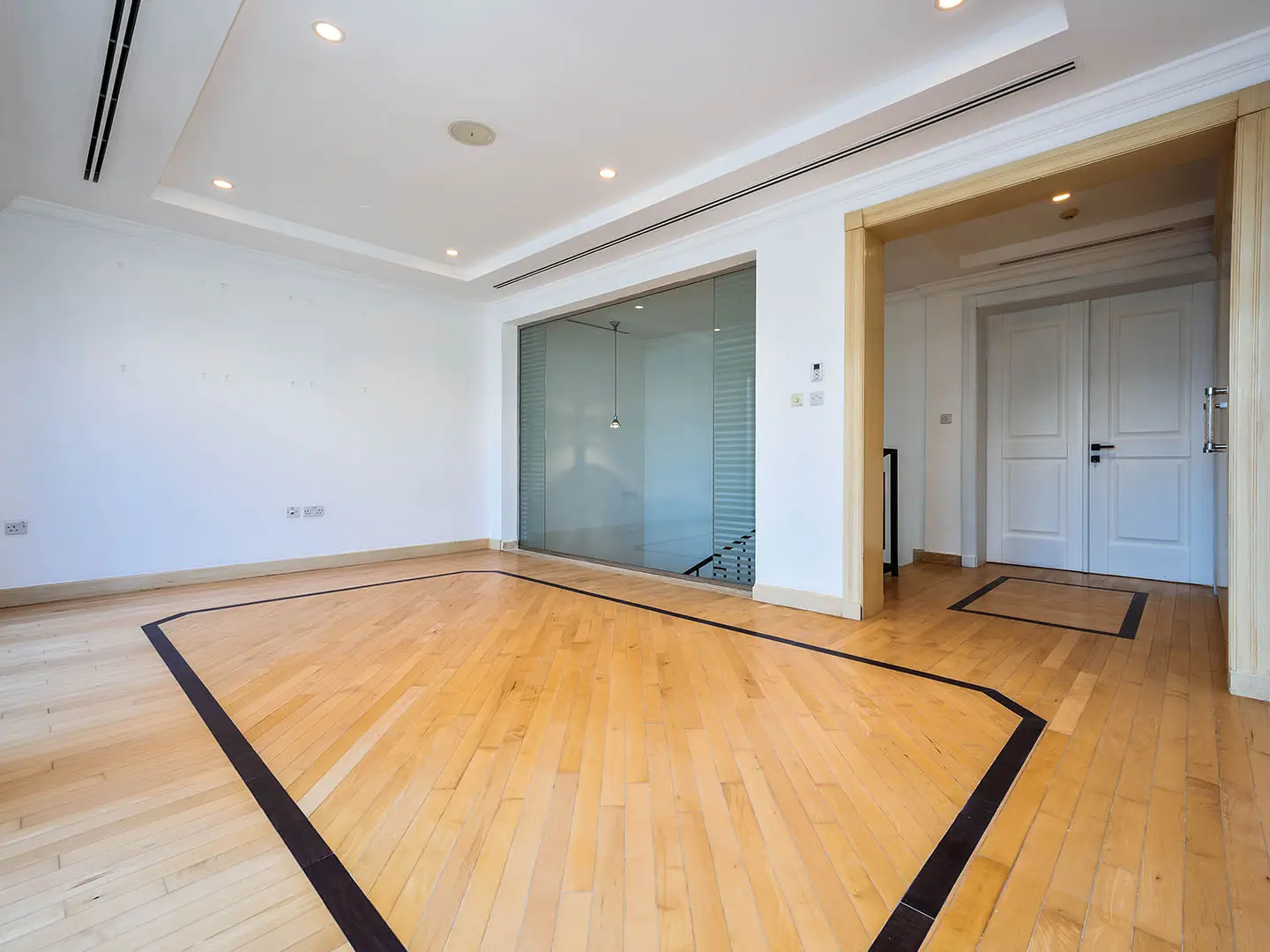 Empty bright room with wooden floor and glass wall