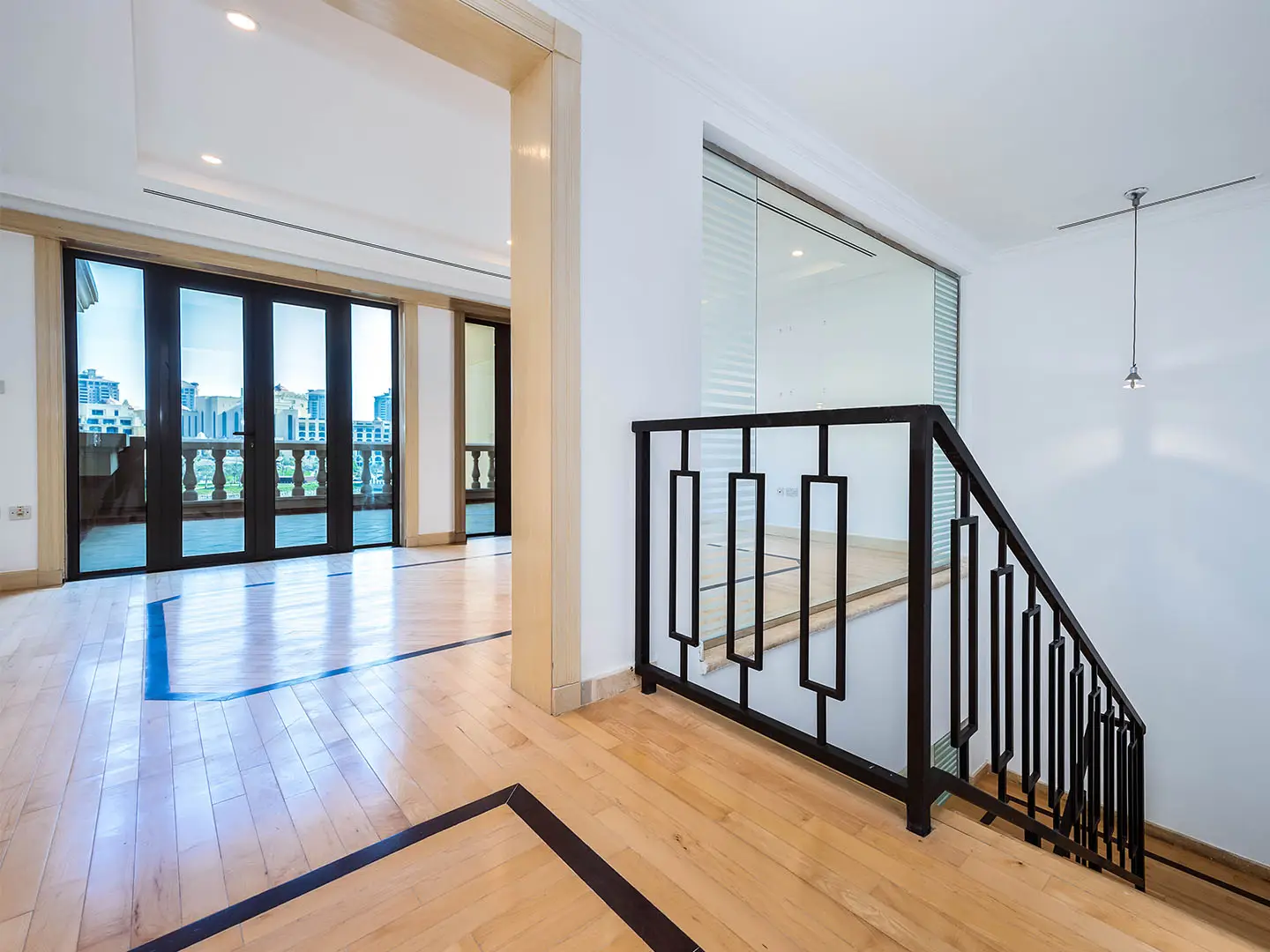 Bright room with wooden floor and black stair railing