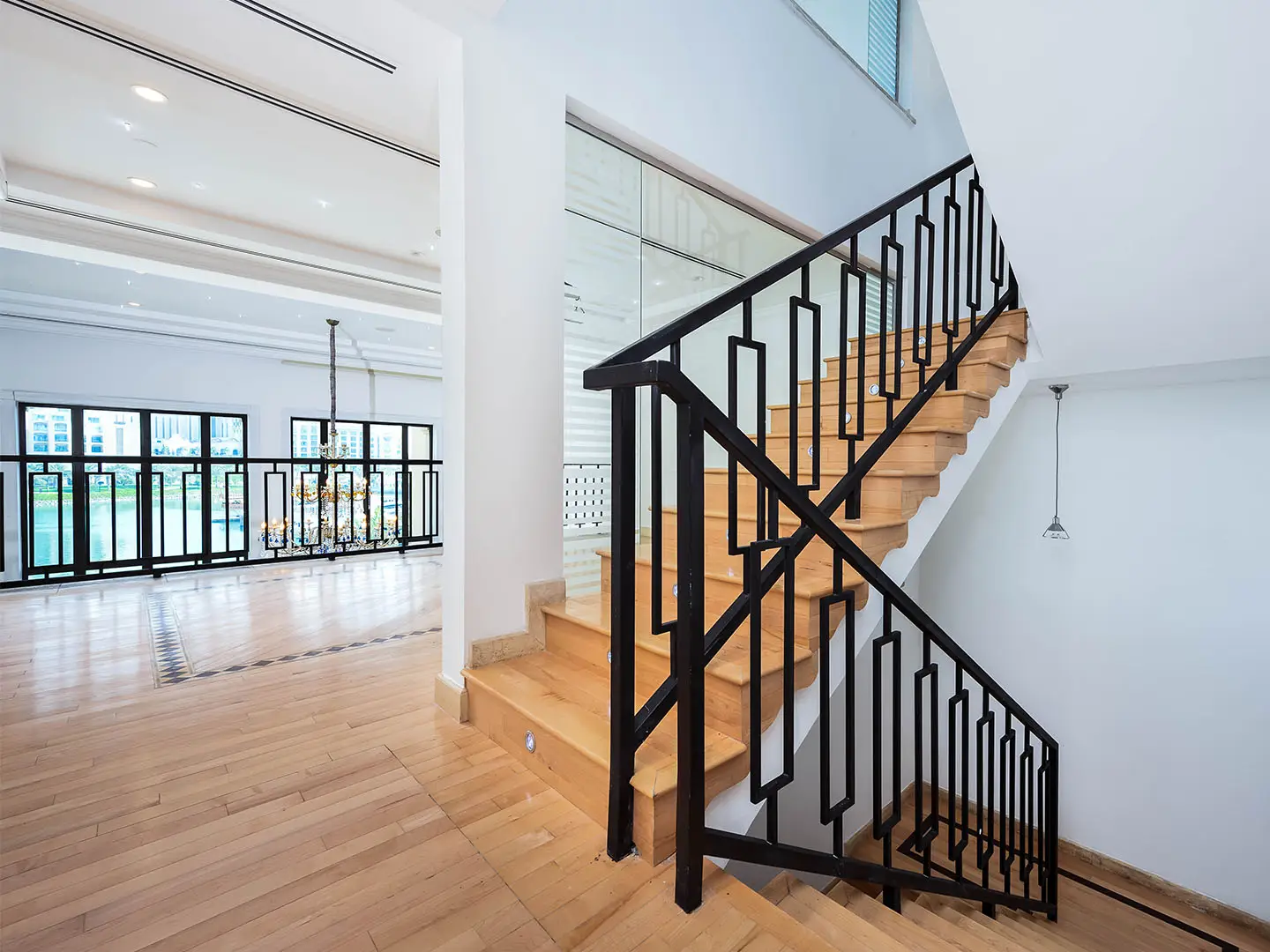 Wooden stairs with black railing in bright empty space