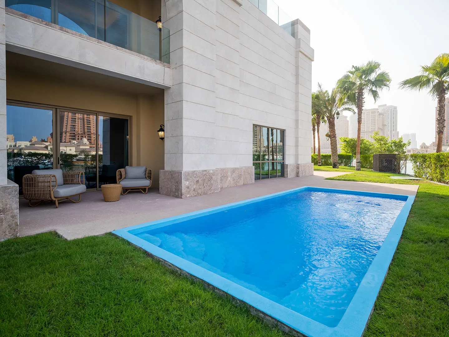 Outdoor pool with patio chairs and palm trees
