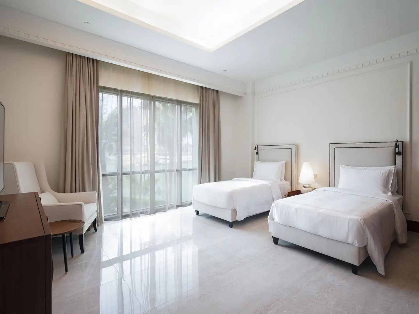 Twin beds bask in morning light through glass