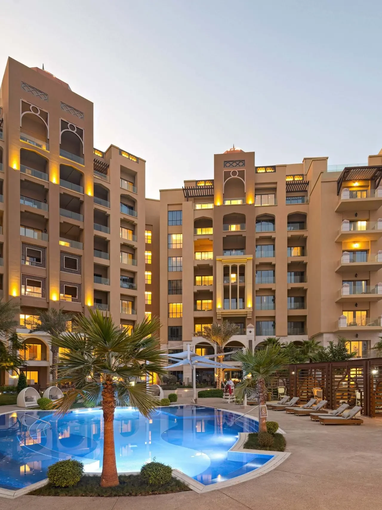 Apartment complex with glowing pool at dusk