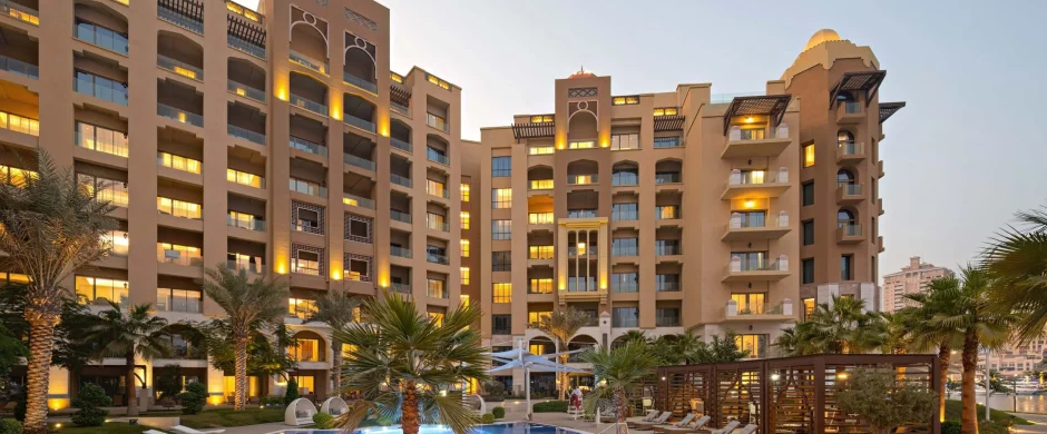 Apartment complex with glowing pool at dusk