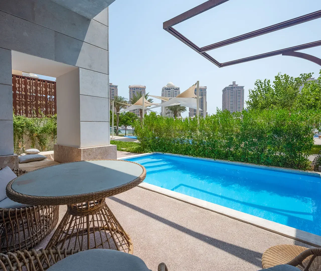 Blue pool beside wicker chairs and table