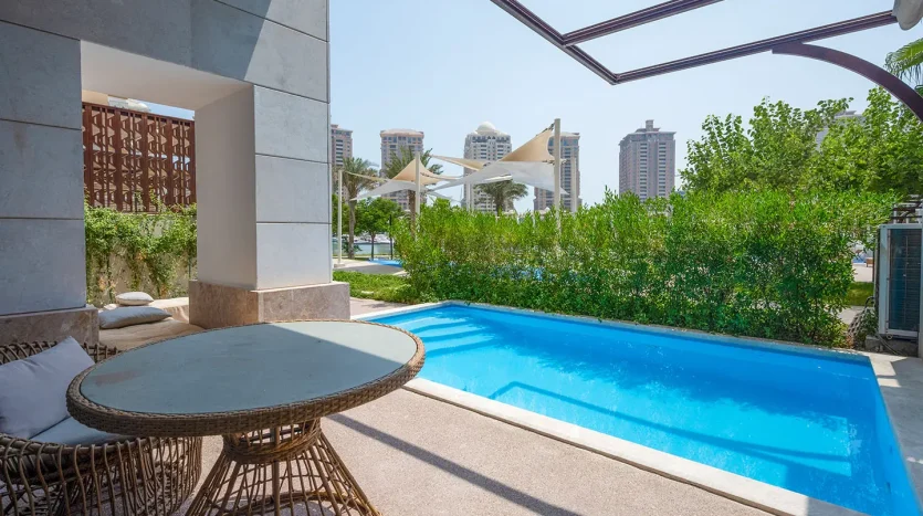 Blue pool beside wicker chairs and table