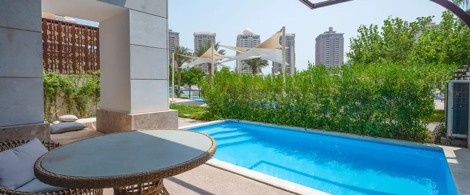 Blue pool beside wicker chairs and table
