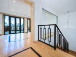 Bright room with wooden floor and black stair railing